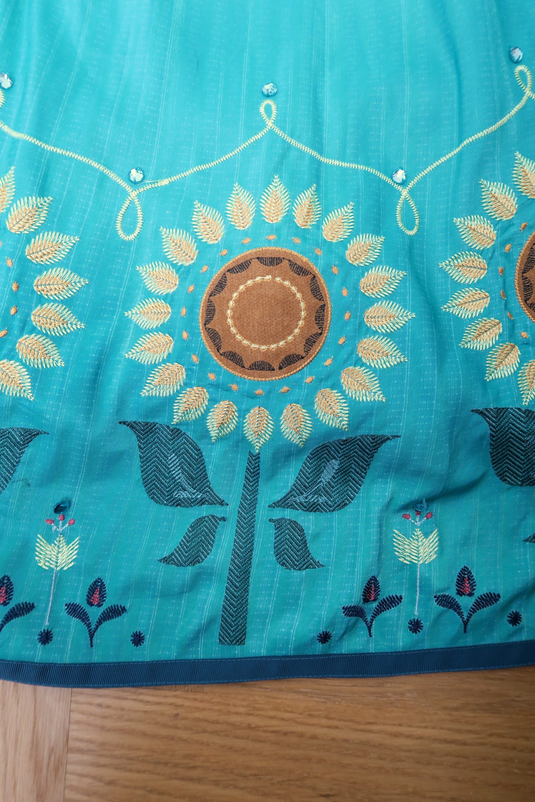 Sunflower embroidery with rhinestones and ribbon around the hem of the skirt